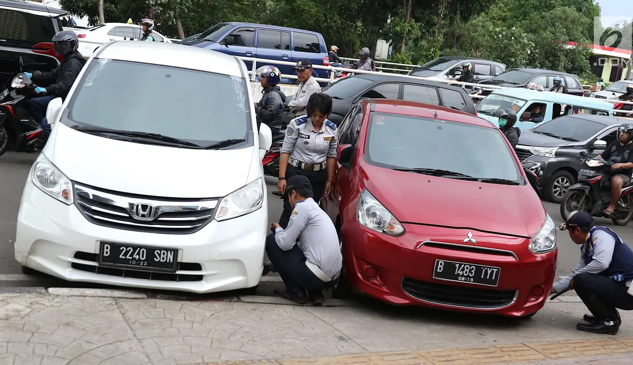 Petugas menderek dan menggembosi ban mobil yang parkir sembarangan di kawasan Tebet, Jakarta, Kamis (28/3). Meskipun berulang kali ditertibakan, namun masih banyak pengendara yang nekat parkir sembarangan sehingga mengganggu arus lalu lintas. (Liputan6.com/Immanuel Antonius)