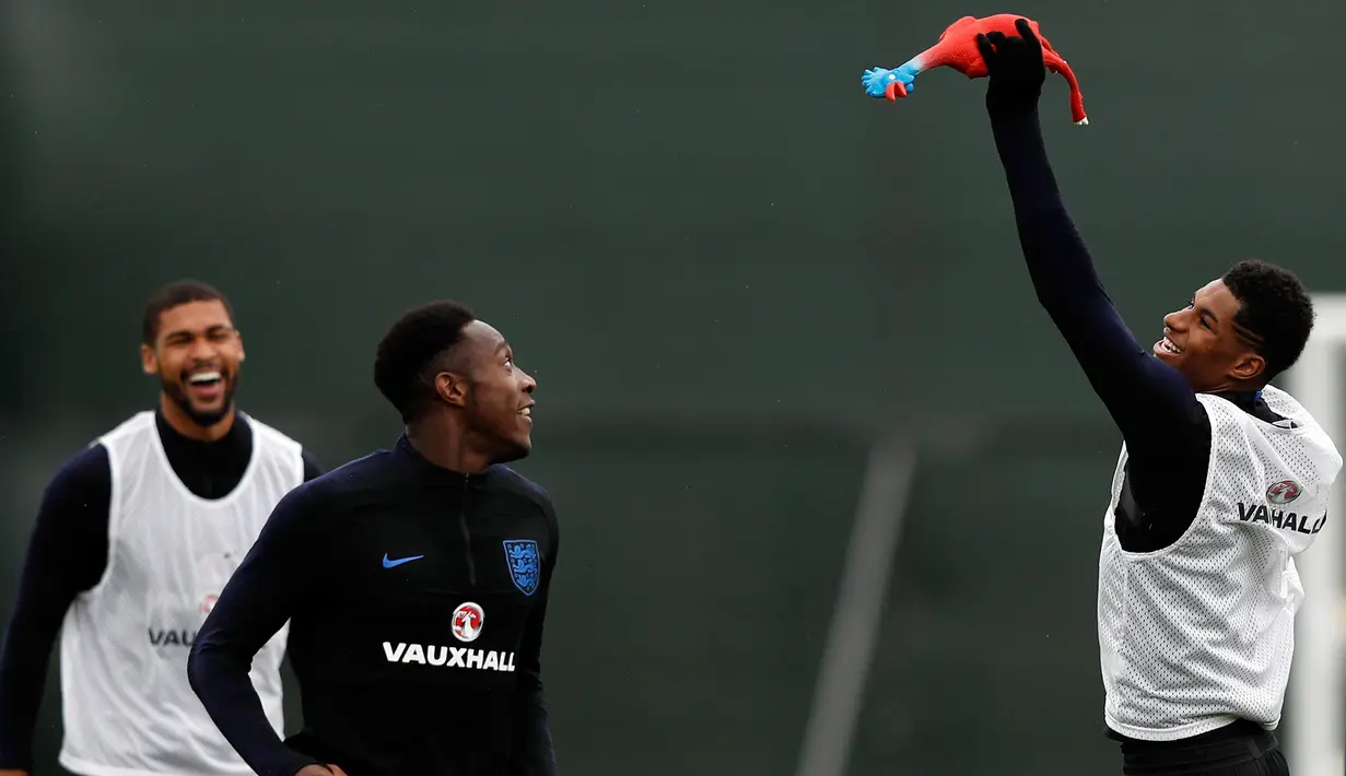 Penyerang Inggris, Marcus Rashford (kanan) menangkap ayam mainan selama mengikuti sesi latihan di Repino, Rusia (10/7). Inggris akan bertanding melawan Kroasia pada babak semifinal Piala Dunia 2018. (AFP Photo/Adrian Dennis)
