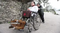 Wanita bernama Li Juhong saat didorong menggunakan kursi roda di Chongqing, Cina. Meski memiliki kekurangan wanita  berusia 37 tahun ini menjadi sebagai dokter umum di desanya. (cnews.chinadaily.com.cn)