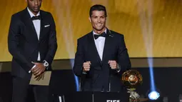 Cristiano Ronaldo (kanan) didampingi Thierry Henry memegang trofi penghargaan Ballon d'Or 2014 di Swiss, Senin (12/1/2015). (AFP PHOTO/Fabrice COFFRINI)