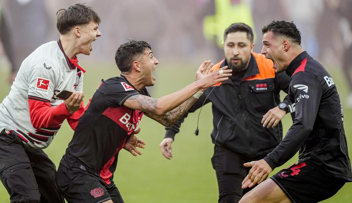 Para pemain dan suporter Bayer Leverkusen merayakannya di lapangan setelah meraih gelar juara Bundesliga 2023/2024 dengan dengan mengalahkan Werder Bremen di BayArena, Minggu (15/4/2024) malam WIB. (AP Photo/Martin Meissner)