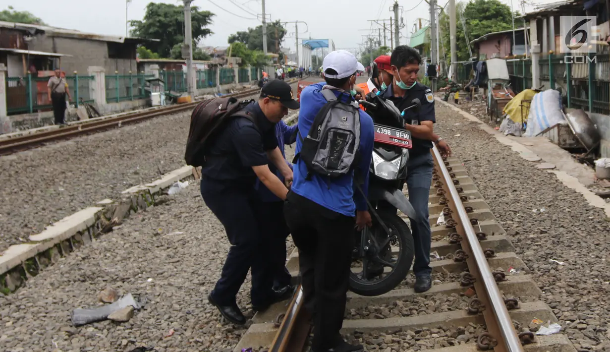 Petugas memindahkan motor warga setempat saat melakukan penertiban lapak dan bangunan liar di sepanjang jalur kereta di kawasan Grogol, Jakarta Barat, Kamis (22/2). (Liputan6.com/Arya Manggala)