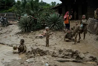 Kondisi lingkungan dan sanitasi yang kurang memadai pasca- bencana dapat memicu peningkatan kasus Infeksi Saluran Pernapasan Akut (ISPA), seperti batuk, pilek, hingga demam. Tampak dalam foto, anak-anak bermain di genangan lumpur di Pengidam, Aceh Tamiang, pada Senin 15 Desember 2025. (Yasuyoshi Chiba/AFP)