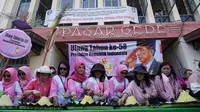 Sejumlah emak-emak dari Komunitas Srikandi Indonesia sedang memotong tumpeng untuk memperingati ulang tahun Presiden Jokowi ke-58 di Pasar Gede Solo, JUmat (21/9).(Liputan6.com/Fajar Abrori)