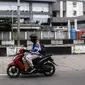 Pengendara sepeda motor melintas dekat tempat karantina pasien COVID-19 Wisma Atlet, Jakarta, Kamis (3/3/2022). Hingga dua tahun berselang, pada 2 Maret 2022, pemerintah mencatat ada 5.630.096 kasus positif COVID-19 di Indonesia sejak pengumuman kasus pertama. (Liputan6.com/Johan Tallo)