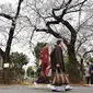 Orang-orang berjalan di Pemakaman Yanaka yang dikelilingi oleh pohon sakura di distrik Taito, Tokyo, Jepang (26/3). Memasuki akhir Maret, pohon bunga sakura mulai bermekaran di sejumlah wilayah Jepang. (AFP Photo/Charly Triballeua)