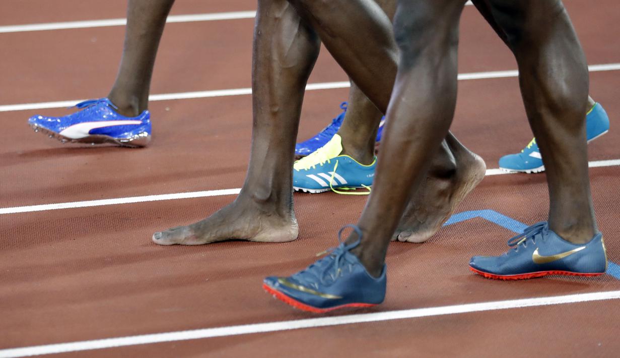 Usain Bolt (tengah) berjalan tanpa mengenakan sepatu usai mengikuti nomor lari estafet 4x100m putra di World Athletics Championships, London (12/8/2017). (AP/Matthias Schrader)