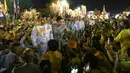 Raja Thailand Maha Vajiralongkorn dan Ratu Suthida menyapa pendukungnya di luar Grand Palace di Bangkok setelah memimpin upacara keagamaan di sebuah kuil Buddha di dalam Istana Raja pada Minggu (1/11/2020). (Jack TAYLOR / AFP)