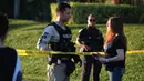 Seorang wanita bertanya kepada petugas kepolisian yang berjaga di lokasi penembakan massal sekolah menengah atas di Parkland, Florida, Rabu (14/2). Pelaku, Nikolaus Cruz (19), menembaki rekannya sesama siswa menggunakan senapan serbu AR-15. (AP PHOTO)