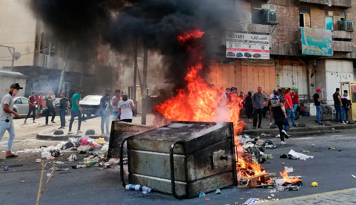 Pengunjuk rasa antipemerintah membakar sejumlah benda dan memblokir jalan saat menggelar protes di Baghdad, Irak, Rabu (2/10/2019). Pengunjuk rasa memprotes korupsi, kegagalan memenuhi layanan publik serta pengangguran. (AP Photo/Hadi Mizban)