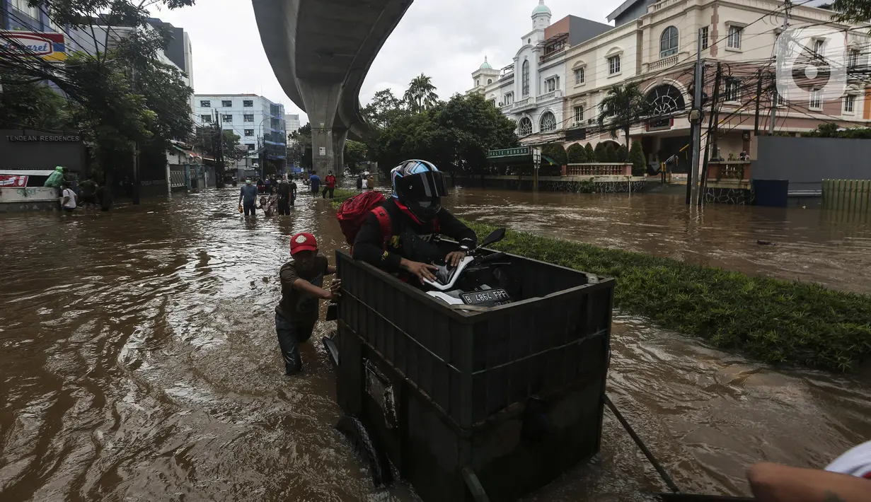 Pengendara sepeda motor menaiki gerobak saat melewati banjir di kawasan Tendean Jakarta, Sabtu (20/2/2021). Curah hujan yang tinggi menyebabkan banjir setinggi orang dewasa di kawasan Tendean. (Liputan6.com/Johan Tallo)