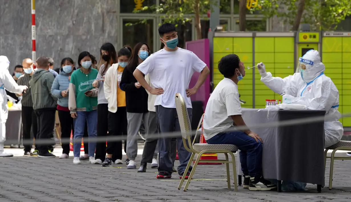 <p>Warga mengantre untuk tes COVID-19 di luar sebuah hotel di Distrik Haidian, Beijing, China, Selasa (26/4/2022). Beijing memberlakukan pengujian massal dan menutup akses ke lingkungan karena berupaya menahan wabah COVID-19 baru. (AP Photo/Ng Han Guan)</p>