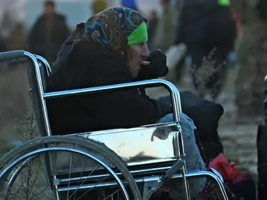 Seorang nenek dari Aleppo timur makan sambil duduk di kursi roda saat tiba di kota al-Rasyidin, Suriah (15/12). Konflik antara pemerintah dan pemberontak membuat kota Aleppo hancur. (REUTERS/Ammar Abdullah)