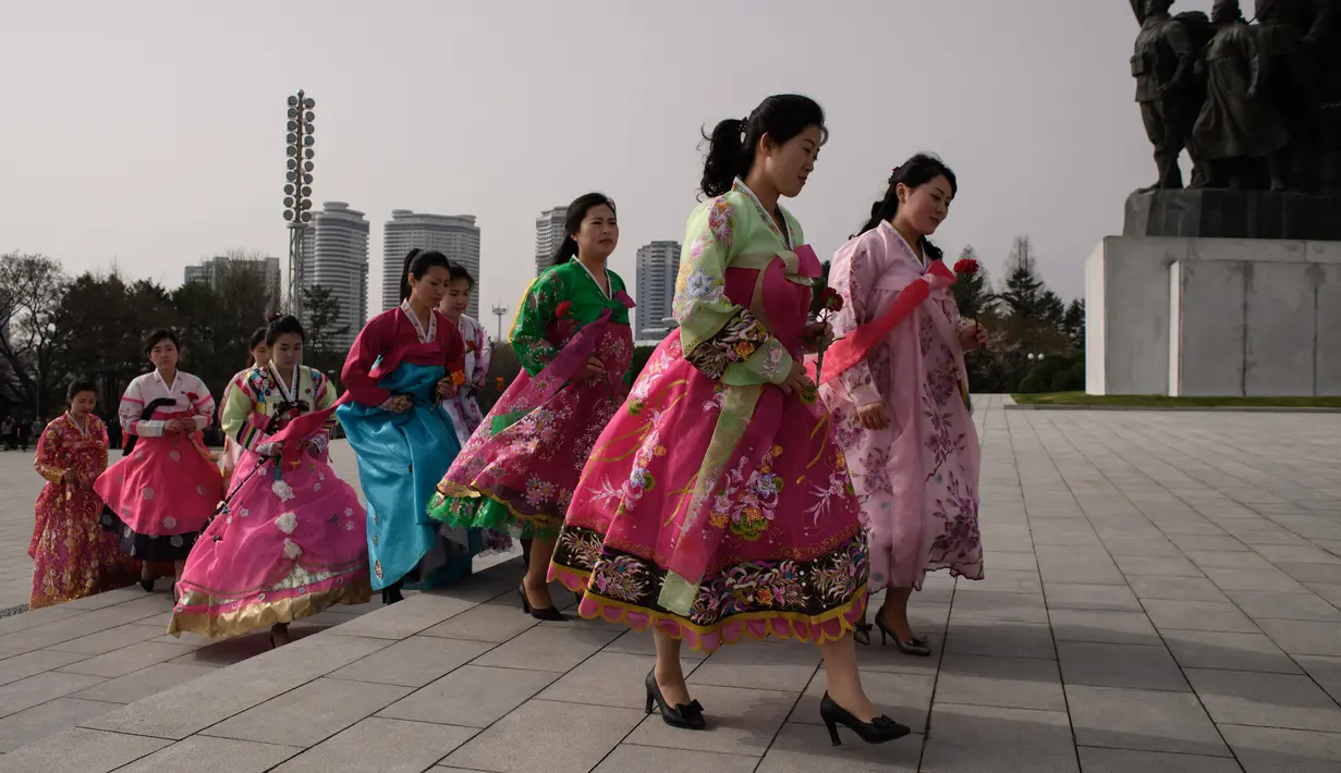 Sejumlah wanita mengenakan pakaian tradsional Korea Utara pergi untuk memberi penghormatan kepada patung-patung pemimpin Korea Utara Kim Il Sung dan Kim Jong Il di Pyongyang (15/4). (AFP Photo/Ed Jones)