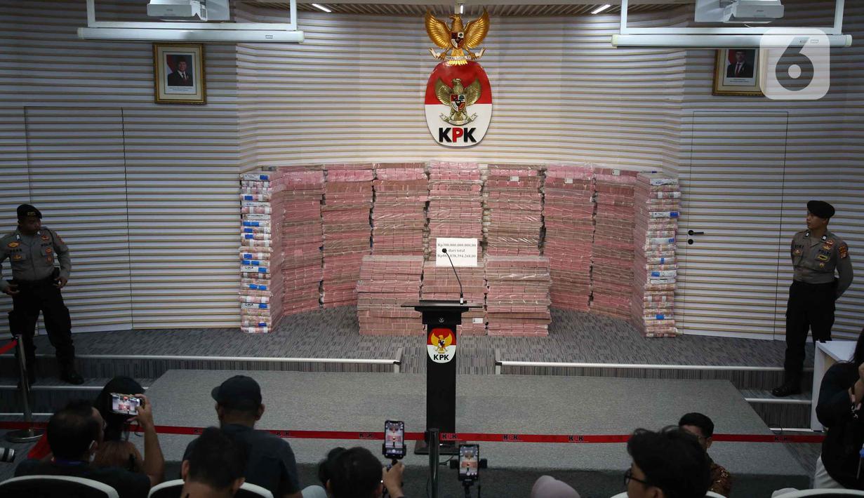 Penyerahan uang ini sebagai bagian dari upaya pemulihan aset negara dan mengembalikan kerugian yang dialami oleh perusahaan dana pensiun Pegawai Negeri Sipil (PNS) tersebut. Tampak dalam foto, polisi berjaga di sisi kiri dan kanan tumpukan uang sebesar Rp 300 miliar dipamerkan di gedung Merah Putih Komisi Pemberantasan Korupsi (KPK), Jakarta, Kamis (20/11/2025). (Liputan6.com/Helmi Fithriansyah)