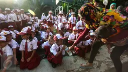 Orangtua memberikan minum pada anaknya sebelum upacara pada hari pertama sekolah di SDN Pasar Baru 05 Jakarta, Senin (18/7). Usai libur Idul Fitri, para siswa kembali mengikuti pelajaran di sekolah untuk tahun ajaran 2015-2016 (Liputan6.com/Faizal Fanani)