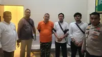 Tersangka penipuan investasi Rp25 miliar (baju oranye) bersama penyidik Reskrimsus Polda Riau. (Liputan6.com/M Syukur)