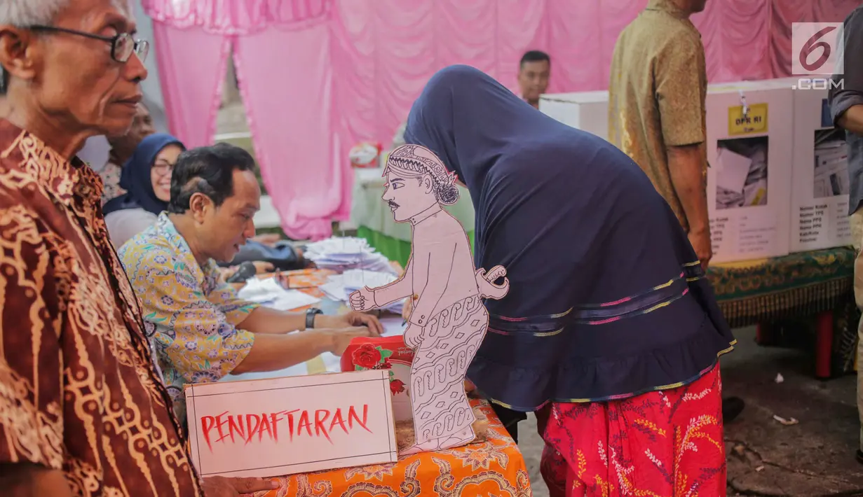 Calon pemilih mendaftar ke petugas Kelompok Penyelenggara Pemungutan Suara (KPPS) saat akan mencoblos di TPS 45 Kebon Pala, Jakarta, Rabu (17/5). TPS tersebut mengambil tema suasana pernikahan adat Jawa untuk menarik minat pemilih dan menekan angka golput. (Liputan6.com/Faizal Fanani)