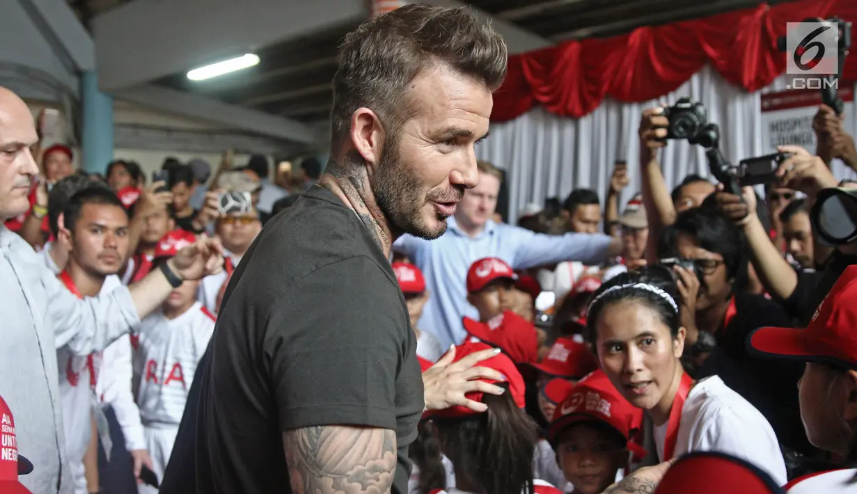 Mantan bintang sepak bola Inggris David Beckham menyapa anak-anak pada acara AIA Sepak Bola untuk Negeri di Jakarta, Minggu (25/3). Kegiatan David dan AIA yaitu membagikan 10 ribu bola untuk akademi sepak bola di Indonesia. (Liputan6.com/Herman Zakharia)