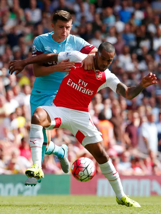 Gelandang Arsenal, Theo Walcott (kiri) berusaha mengontrol bola dari kejaran bek West Ham, Aaron Cresswell pada pertandingan Liga Primer Inggris di Stadion Emirates, London, (9/8/2015). West ham menang 2-0 atas Arsenal. (Reuters/Eddie Keogh)