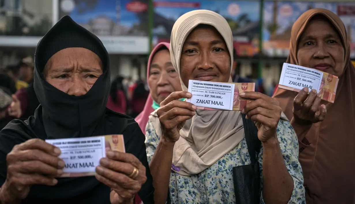 Jumlah ini naik 100 persen dibandingkan tahun lalu yang tercatat sekitar 16 ribu penerima. Guna menghindari penumpukan warga, penyaluran dilakukan secara bertahap selama 12 hari. Tampak dalam foto, warga memperlihatkan uang hasil pembagian zakat di Masjid Cheng Hoo, Surabaya, Jawa Timur pada Rabu 4 Maret 2026. (JUNI KRISWANTO/AFP)