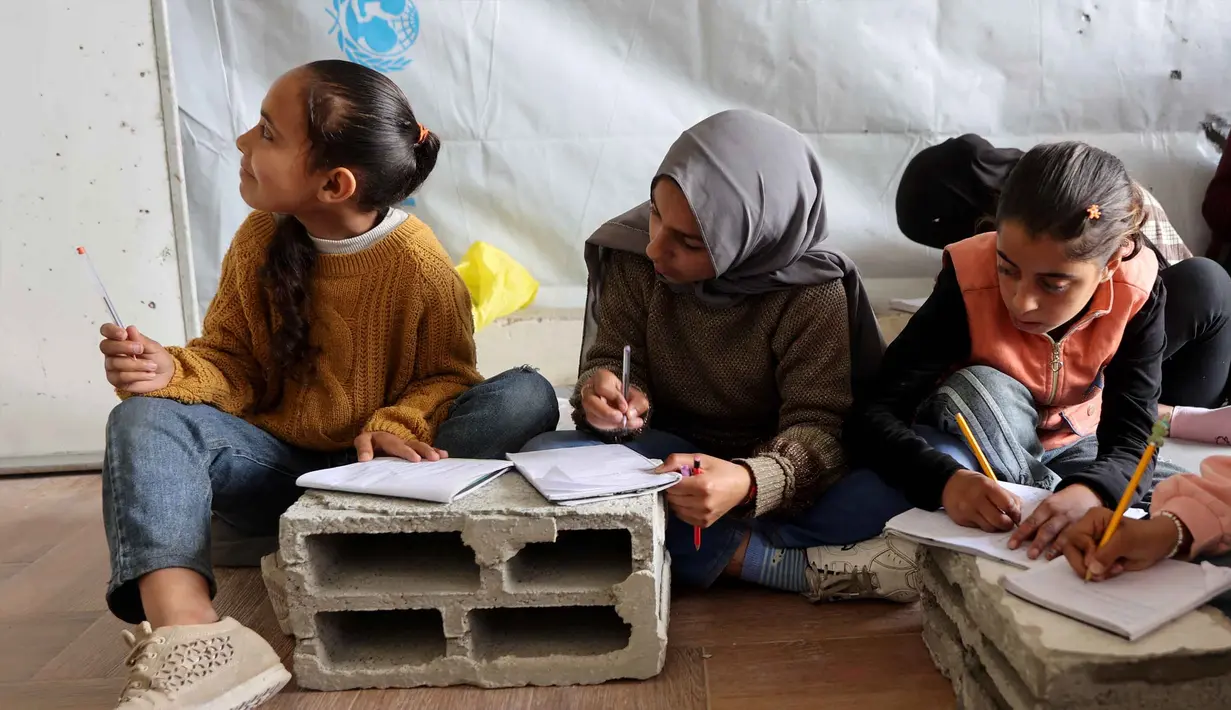 Sekolah Mada menjadi ruang untuk melanjutkan proses belajar bagi anak-anak pengungsi Palestina yang terpaksa meninggalkan rumah mereka. Tampak dalam foto, anak-anak pengungsi Palestina mengikuti belajar mengajar di dalam tenda di Sekolah Mada, kamp pengungsi Jabalia, Jalur Gaza Utara pada 13 April 2026. (Omar AL-QATTAA/AFP)