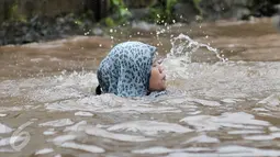Seorang wanita terjatuh ke dalam lubang yang tak terlihat saat melintasi banjir di Jalan Taman Bukit Duri, Jakarta Selatan, Selasa (21/2). (Liputan6.com/Yoppy Renato)