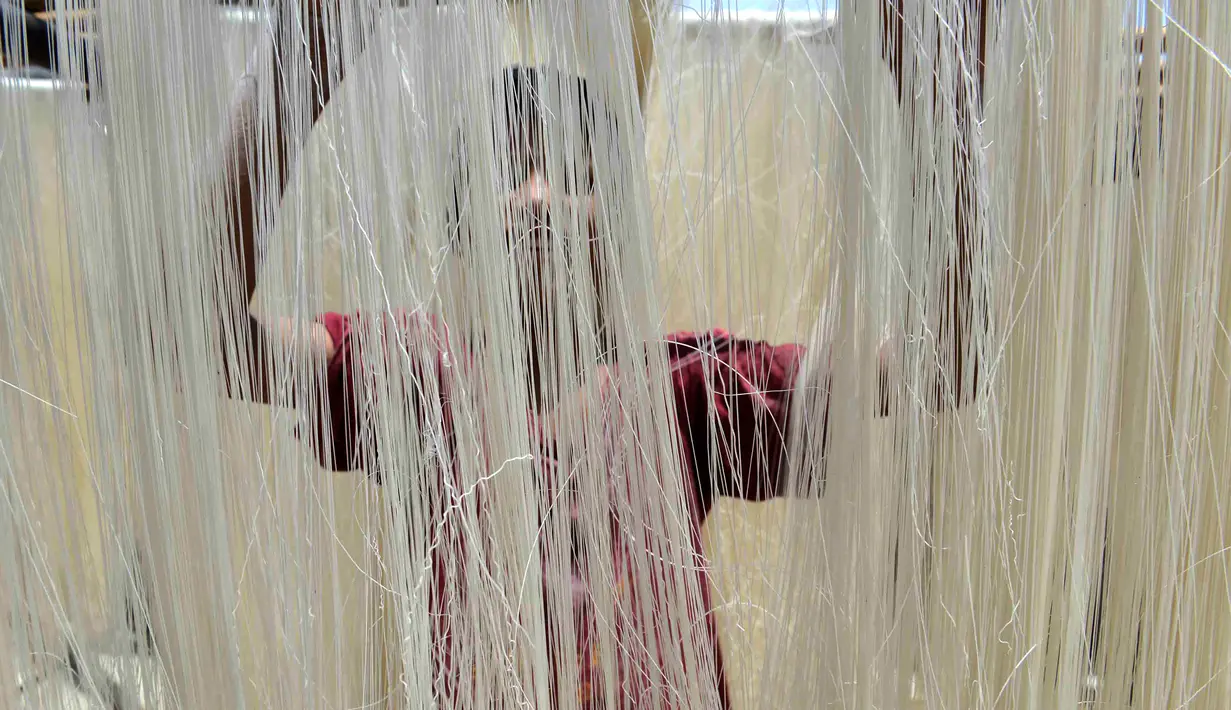 Seorang pekerja sedang menjemur bihun saat proses pembuatan Sheerkhorma di Allahabad, India, 16 Juni 2016. Sheerkhorma merupakan hidangan manis tradisional khas Ramadan bagi muslim di India. (Noah SEELAM/AFP)