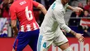 Bek Real Madrid, Sergio Ramos berebut bola dengan gelandang Atletico Madrid, Koke pada laga pekan ke-12 La Liga di Stadion Wanda Metropolitano, Sabtu (18/11). Laga Derbi Madrid itu berakhir imbang tanpa gol (CURTO DE LA TORRE/AFP)