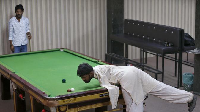 Mohammad Ikram bermain snooker dengan dagunya di sebuah klub snooker lokal di kota Samundri, Pakistan, Minggu (25/10/2020). Dia tinggal di kota pedesaan terpencil di provinsi Punjab dan kecacatan fisiknya tidak menghalangi impian masa kecilnya untuk bermain snooker. (AP Photo/Anjum Naveed)