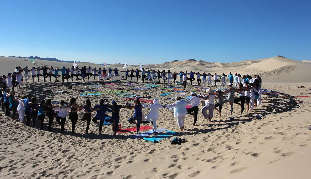 Peserta menghadiri kelas yoga yang diselenggarakan oleh komunitas YSYoga System di gurun Samalayuca, negara bagian Chihuahua, Meksiko pada 25 Mei 2019. Latihan di atas pasir gurun yang terik ini menjadi tantangan tersendiri bagi para pencinta Yoga. (Herika MARTINEZ/AFP)