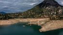 Foto ini menunjukkan sisa-sisa rumah yang muncul kembali ketika permukaan danau buatan Mornos menurun akibat kekeringan, di desa Kallio, sekitar 240 km barat laut Athena, Yunani pada 3 November 2025. Kemunculan kembali desa tersebut disebabkan oleh kekeringan parah dan tingkat air danau yang menurun drastis ke level terendah dalam beberapa dekade, akibat musim dingin dengan sedikit salju, gelombang panas, dan curah hujan yang rendah di Yunani. (Angelos TZORTZINIS/AFP)