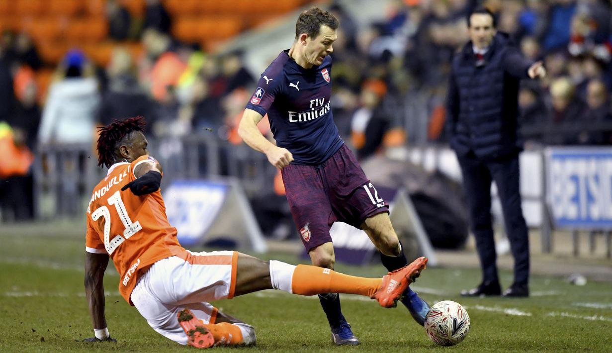 Bek Arsenal, Stephan Lichtsteiner, berebut bola dengan pemain Blackpool, Armand Gnanduillet, pada laga Piala FA di Stadion Bloomfield Road, Sabtu (5/1). Arsenal menang 3-0 atas Blackpool. (AP/Anthony Devlin)