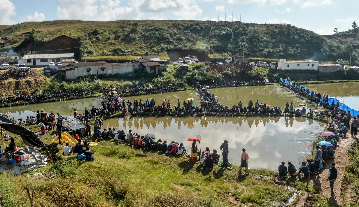 Para peserta pria berkonsentrasi dengan kailnya pada kompetisi memancing di sebuah kolam dekat desa Weilei di Negara Bagian Meghalaya, timur laut India, Sabtu (21/9/2019). Ratusan peserta berpartisipasi dalam kompetisi yang memperebutkan sejumlah hadia tersebut. (DIPTENDU DUTTA / AFP)