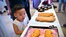 Seorang anak melihat pameran kue bulan dalam acara perayaan Festival Pertengahan Musim Gugur di Museum Hainan, Haikou, ibu kota Provinsi Hainan, China selatan (1/10/2020). (Xinhua/Guo Cheng)