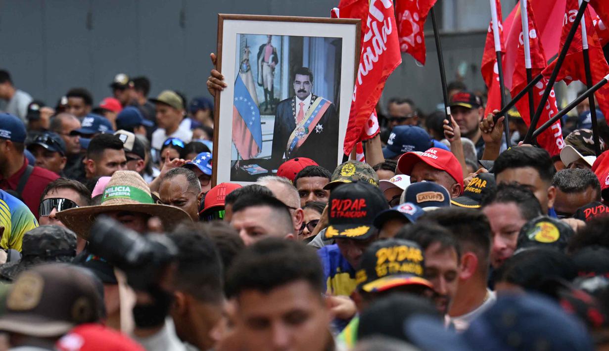 Sebelumnya, Presiden Nicolas Maduro bersama istrinya, Cilia Flores, ditangkap oleh pasukan AS di kediaman mereka di Caracas pada Sabtu 3 Januari 2026 dini hari waktu setempat. Tampak dalam foto, potret mantan Presiden Venezuela Nicolas Maduro terlihat saat aksi unjuk rasa digelar para pendukungnya di Caracas pada Minggu 4 Januari 2026. (Juan BARRETO/AFP)
