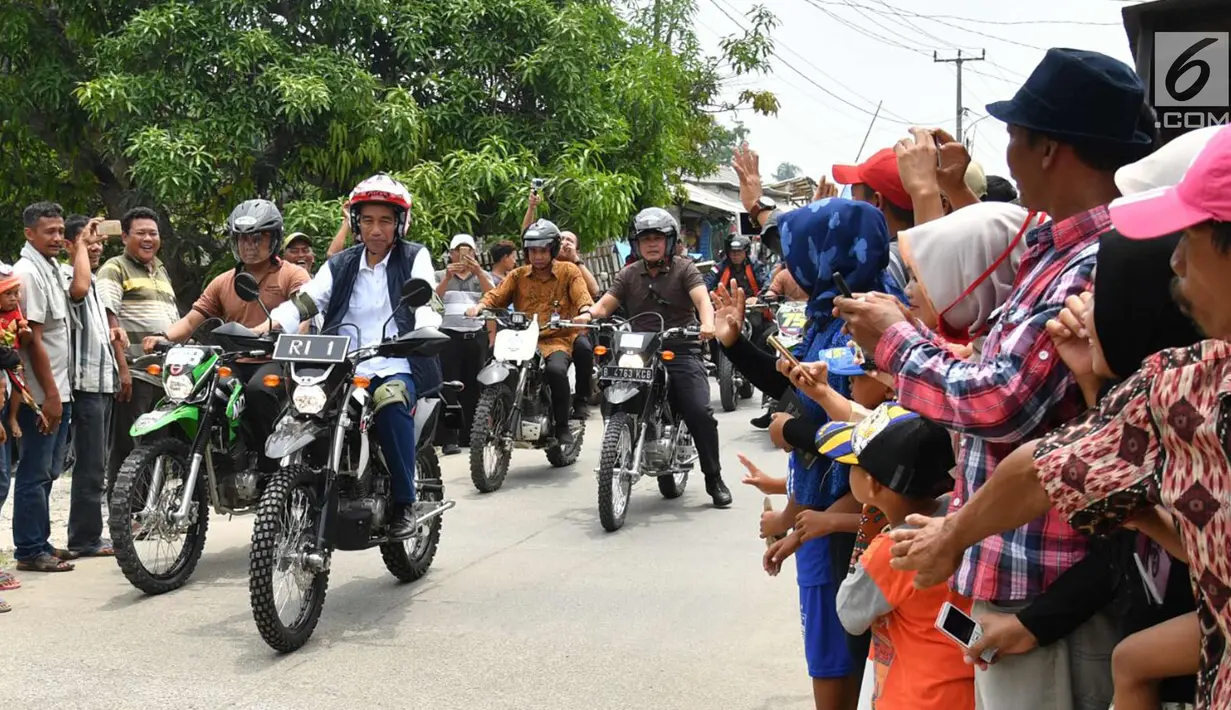 Warga menyambut kedatangan Presiden Joko Widodo saat mengendarai motor trail di Muara Gembong, Bekasi (1/11). Jokowi mengenakan kemeja putih, celana jeans, dengan balutan jaket rompi berwarna hitam. (Liputan6.com/Biro Pers Kepresidenan/Agus Suparto)