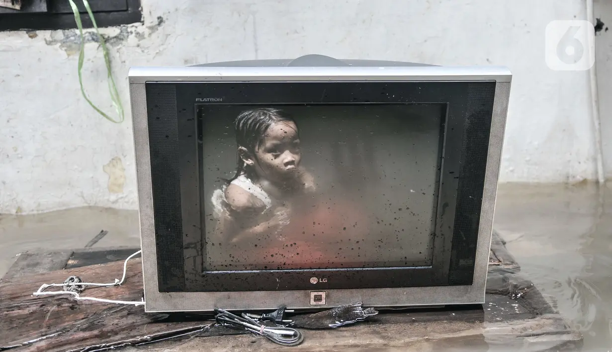 Refleksi anak terlihat dari televisi saat banjir merendam kawasan Kemang Timur XI, Jakarta Selatan, Minggu (21/2/2021). Longsor yang merusak rumah dan menutup aliran kali membuat RT 10 dan 12, RW 03, Kelurahan Bangka, Kecamatan Mampang Prapatan masih terendam banjir. (merdeka.com/Iqbal S. Nugroho)