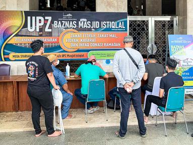 Sejumlah umat muslim antre untuk membayar zakat fitrah di Masjid Istiqlal, Jakarta, Jumat (29/4/2022). Panitia Zakat Masjid Istiqlal mulai membuka layanan pembayaran zakat fitrah dengan pembayaran senilai Rp 50 ribu atau 3,5 liter beras. (Liputan6.com/Faizal Fanani)
