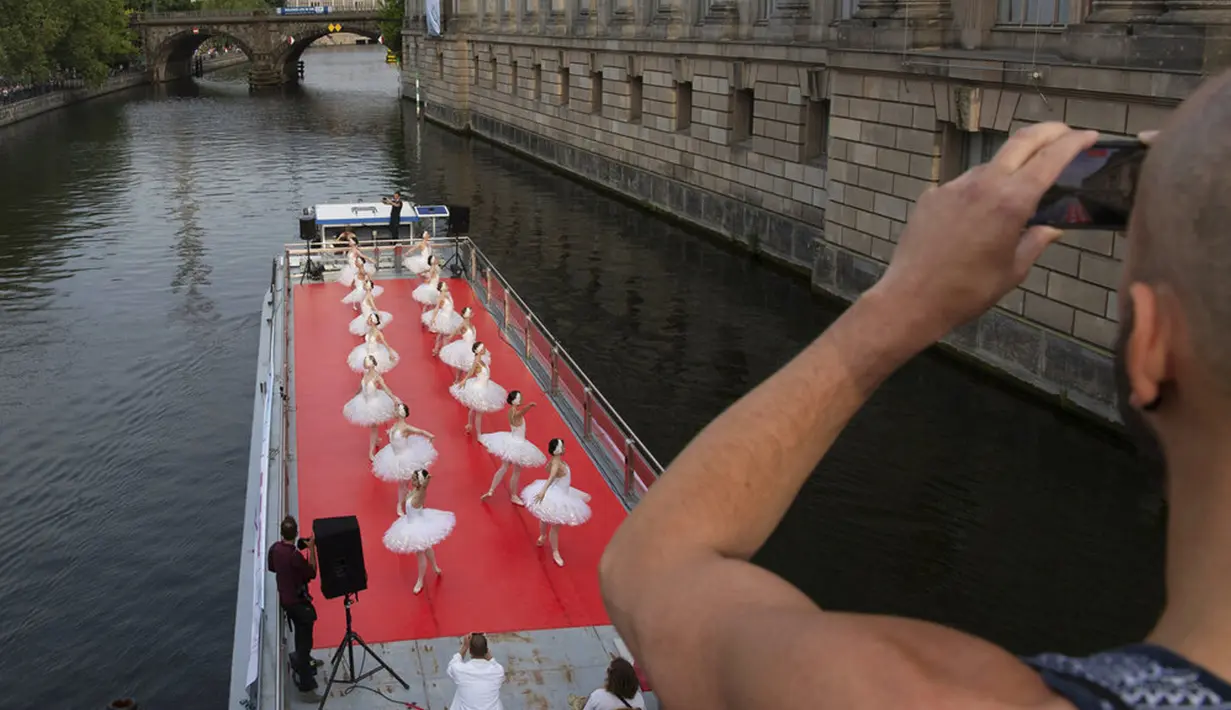 Anggota Staatsballett Berlin menari di atas kapal pesiar selama tur melalui pusat kota di Berlin, Jerman, Kamis (10/6/2021). Pertunjukan itu diikuti oleh banyak orang di sepanjang rute. (Paul Zinken/dpa via AP)
