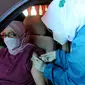 Paramedis menyuntikkan vaksin COVID-19 secara drive thru kepada penumpang mobil di GOR Pajajaran, Kota Bogor, Jawa Barat, Rabu (17/3/2021). Kegiatan ini diselenggarakan oleh Halodoc, Gojek, dan Pemkot Bogor. (merdeka.com/Arie Basuki)