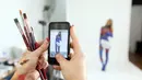 Menggunakan kamera telepon genggam, seniman Jade Little mengabadikan karyanya yang ditorehkan di tubuh model cantik Renee Somerfield, Sydney, (3/7/2014). (REUTERS/Jason Reed)