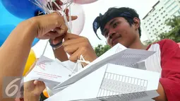 Seorang aktivis mengikat surat pesawat kertas yang akan diterbangkan dengan balon, Jakarta, Minggu (29/5/2016). Surat pesawat kertas tersebut ditujukan untuk Jokowi agar melindungi anak Indonesia dari bahaya rokok. (Liputan6.com/Yoppy Renato) 
