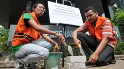 Dua orang dari Anggota Koalisi Pemantau Peradilan saat akan meletakkan batu pertama pembangunan museum KPK di halaman KPK, Jakarta, Kamis (8/10/2015). Mereka memprotes DPR yang berencana merevisi UU KPK NO.30 th 2002 (Liputan6.com/Andrian M Tunay)