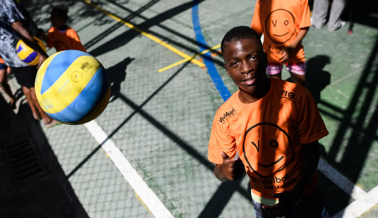 Seorang anak mencoba melambungkan bola voli pada program Volleyball Development Training yang digagas oleh FIVB di Formiga favela, Rio de Janeiro, (2/8/2016). (AFP/Leon Neal)