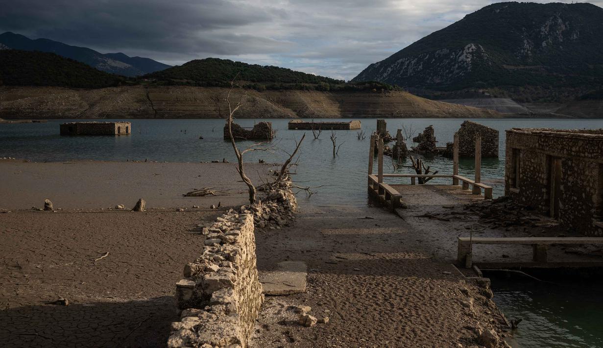 Foto ini menunjukkan sisa-sisa rumah yang muncul kembali ketika permukaan danau buatan Mornos menurun akibat kekeringan, di desa Kallio, sekitar 240 km barat laut Athena, Yunani pada 3 November 2025. Untuk diketahui, danau buatan Mornos sengaja dibuat pada akhir tahun 1970-an dan awal 1980-an untuk menyediakan pasokan air bagi hampir separuh populasi Yunani, termasuk ibu kota Athena, yang membuat desa asli Kallio sengaja ditenggelamkan. (Angelos TZORTZINIS/AFP)