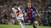 Gelandang Rayo Vallecano Oscar Valentin (kiri) bersaing dengan pemain Barcelona Frenkie De Jong dalam laga Liga Spanyol di Camp Nou, Minggu (14/8/2022) dini hari WIB. (Pau BARRENA / AFP)