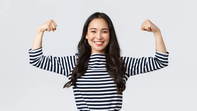 Seorang perempuan berbaju garis hitam putih sedang mengangkat kedua lengannya dengan berpose bisep (Foto Dok: Freepik/benzoix)
