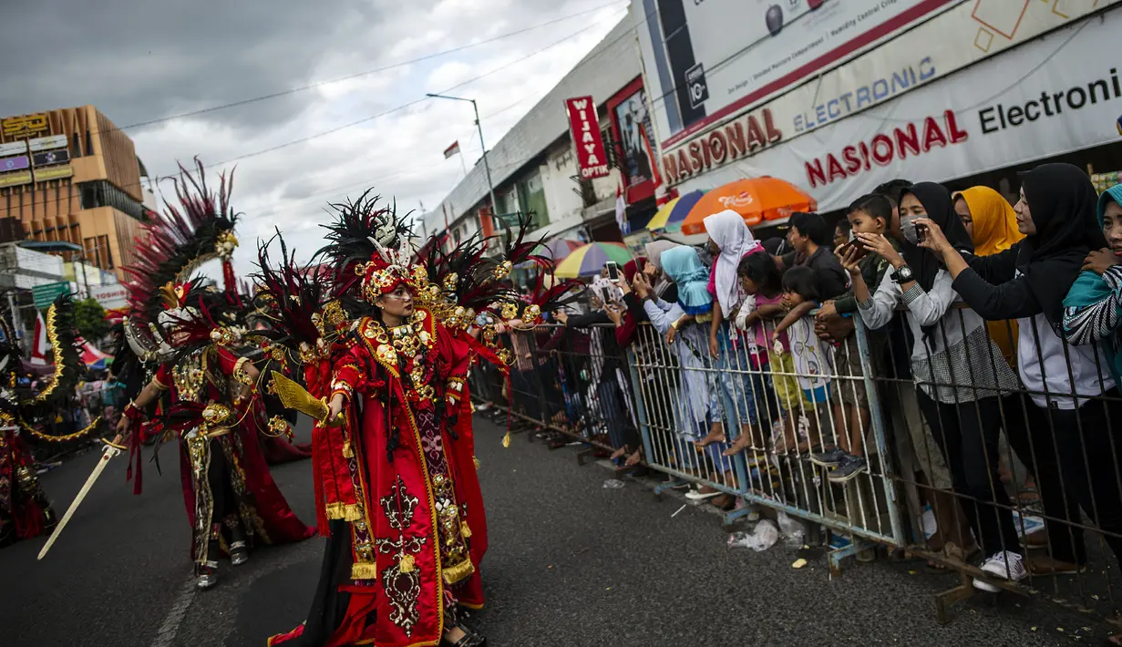 Warga menyaksikan peserta menampilkan kreasi kostum dalam Jember Fashion Carnaval (JFC) di Jember, Provinsi Jawa Timur pada Minggu (4/8/2019). Kegiatan ini mengangkat tema 'tribal grandeur', dengan menghadirkan keagungan 8 suku di dunia. (Photo by JUNI KRISWANTO / AFP)