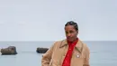 A$AP Rocky mencuri perhatian dengan layering smart-casual: jaket suede beige dipadu kemeja merah bold dan celana tailored, dilengkapi tas Chanel pink statement yang playful sekaligus sentimental. [Dok/Chanel].